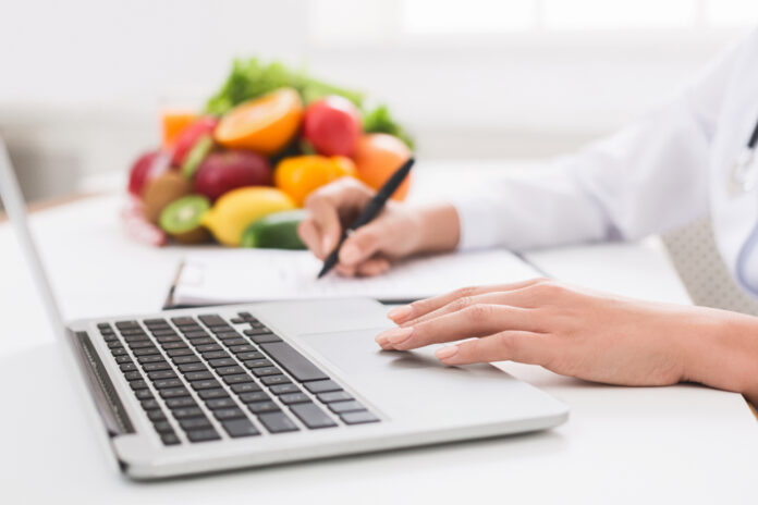 Nutritionist,Working,On,Laptop,And,Writing,Diet,Plan,For,Patient,